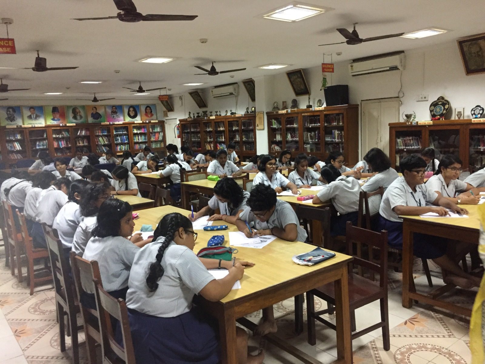 Girl students writing at tables in a school library