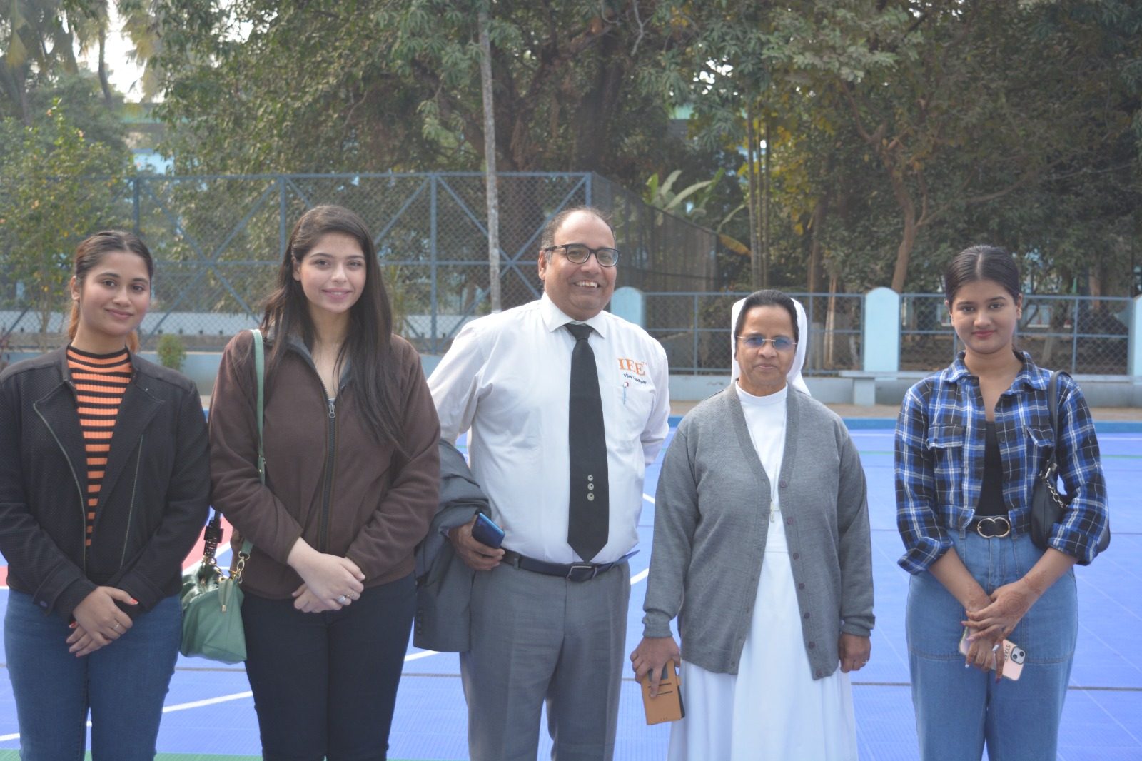 Group of five people standing on a blue sports court