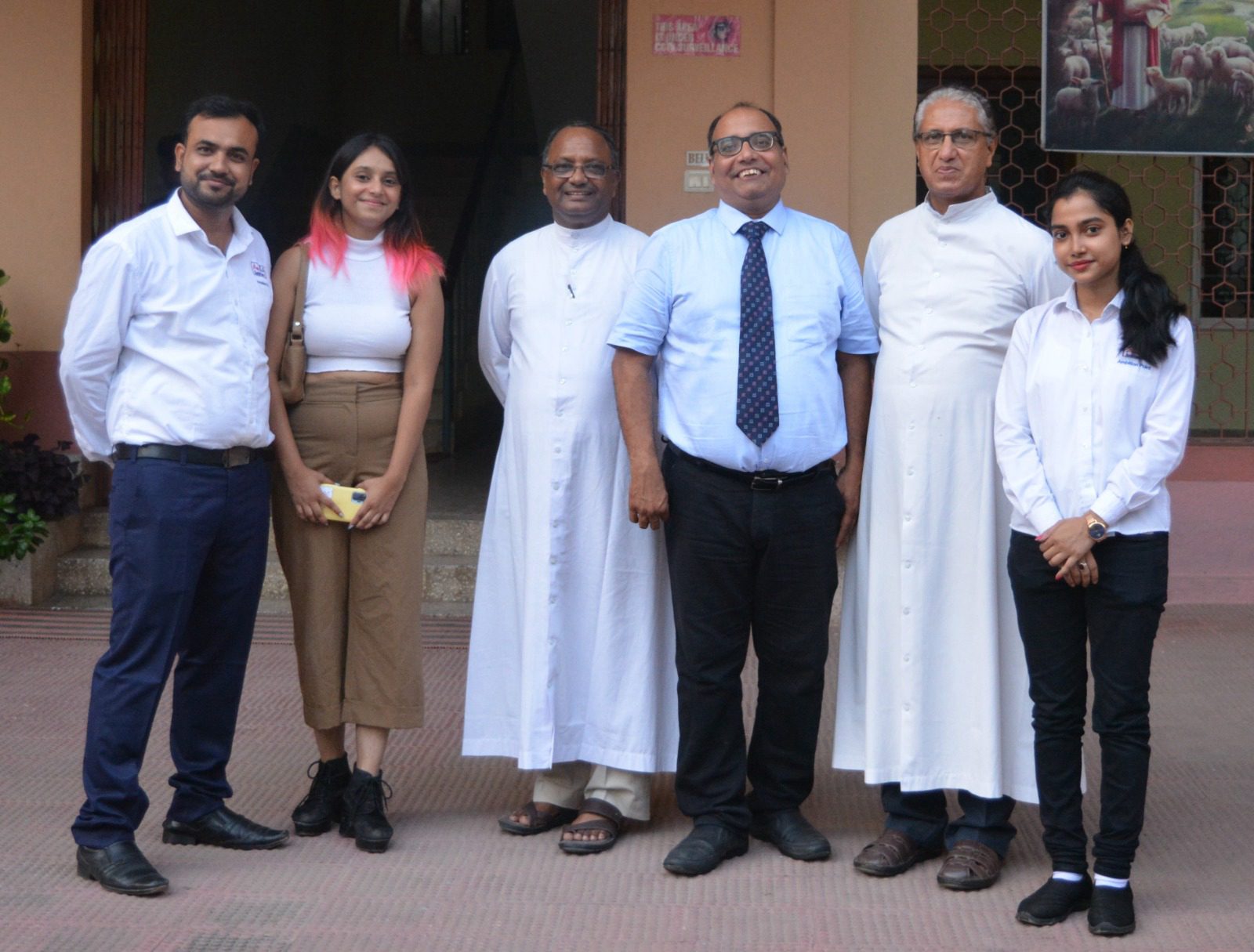 Six people standing together outside a building entrance