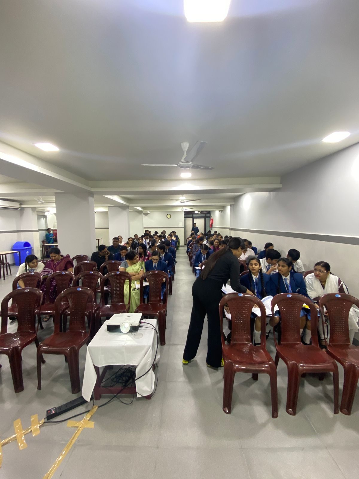 Students and parents seated in rows in a hall with a projector at the front