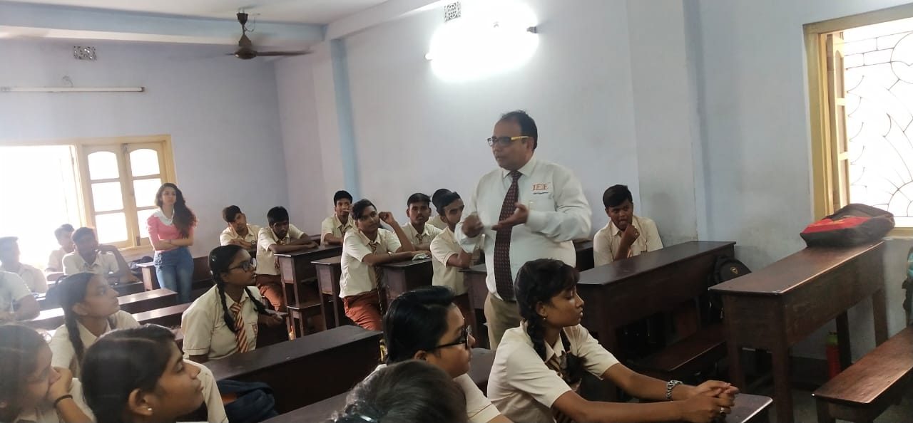 Speaker addressing students in cream uniforms in a classroom