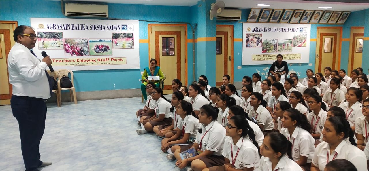 Speaker with a microphone addressing girl students seated in a hall