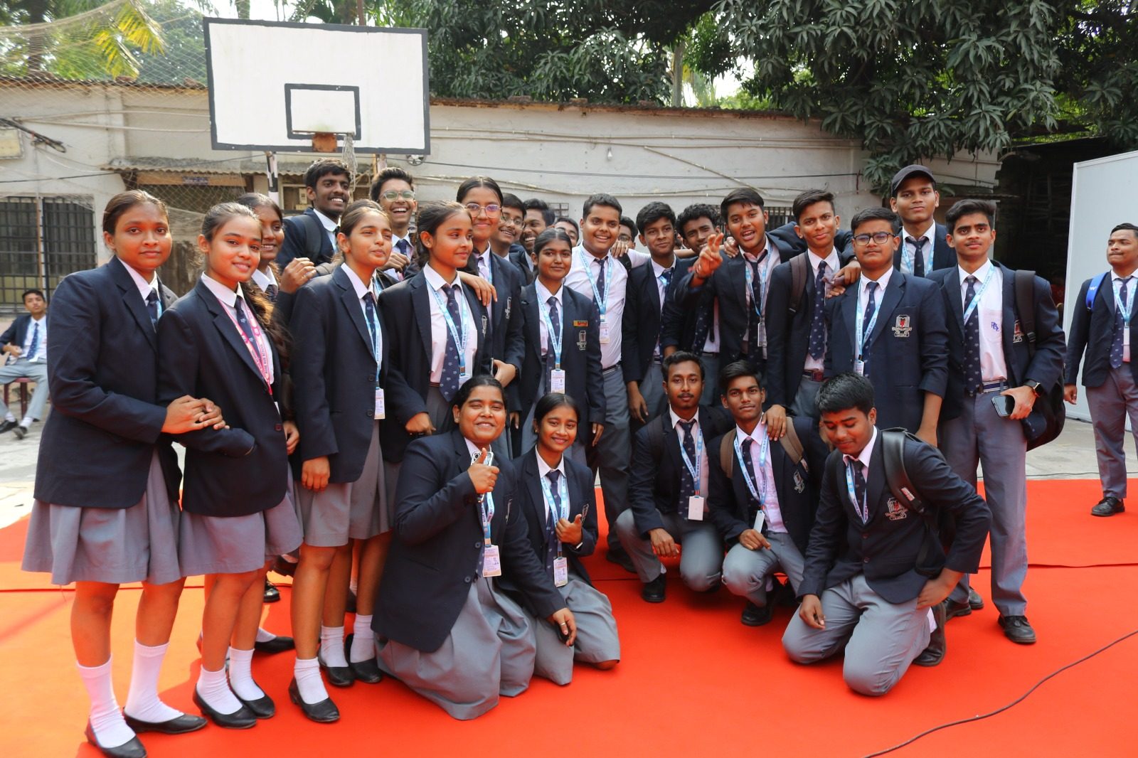 Students in navy blazers posing for a group photograph on a red carpet at a career fair
