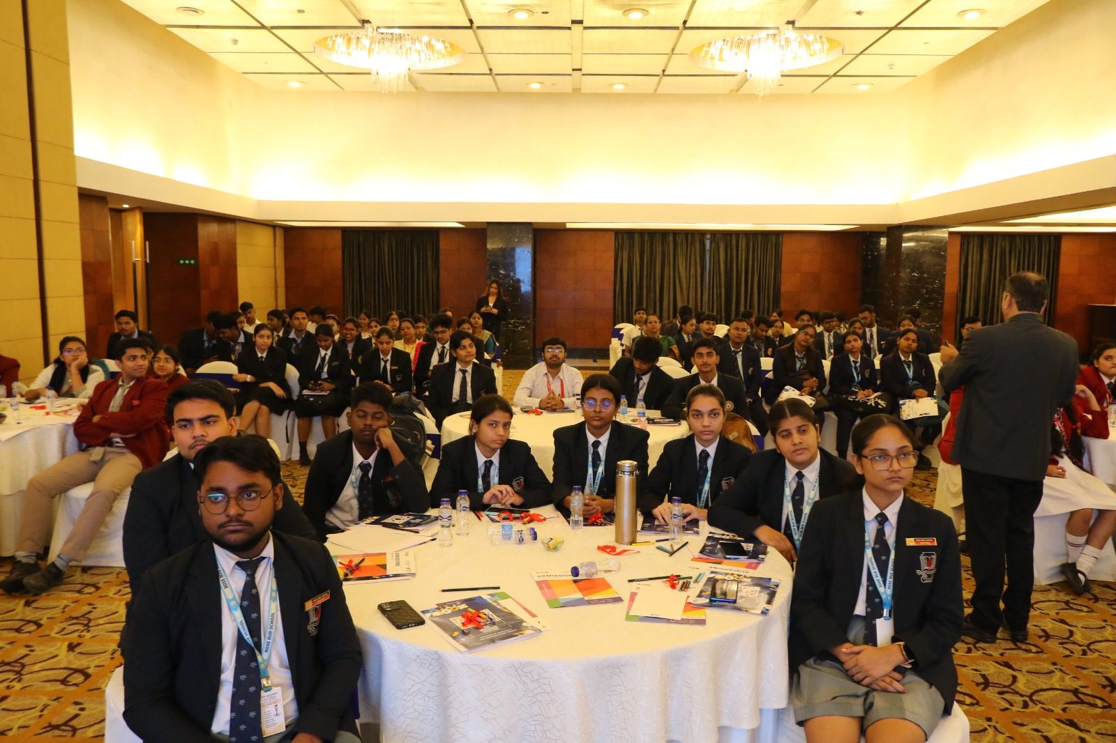 Students seated at round tables with brochures in a banquet hall during a career event