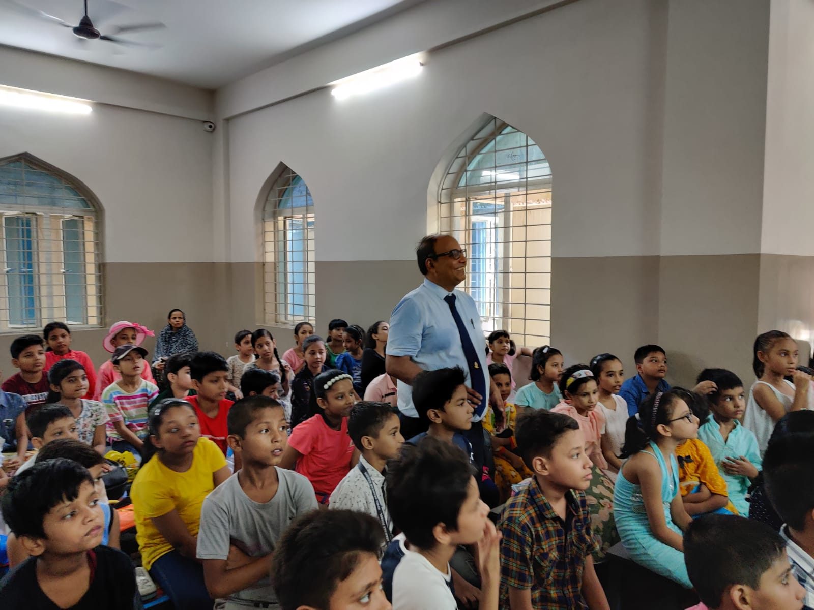 Speaker standing among young school children seated in a classroom